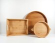 Three natural wood trays different shapes and sizes are arranged on white background. Rectangular and round serving platters, kitchenware objects with handles, empty for food presentation.