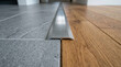 © INT888 - Transition strip between gray tile and wood floor, close up interior detail, metal threshold trim, floor seam, home renovation