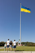 © Anna - Four people standing next to each other under large flag raised high in Kyiv. stand with Ukraine. National identity. Independence Day. Freedom, trust, pride, national symbol, support . Stop the war.