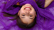 © Kondor83 - Happy Hispanic woman lying of violet silk sheets