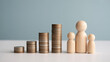 © Syedali - A family of wooden figures standing next to stacks of coins representing financial growth and savings