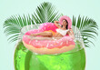 © New Africa - Attractive woman with swim ring in glass of cocktail against light blue background