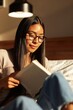 © Andrii Zastrozhnov - Young woman reading book on bed under lamp light in evening