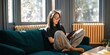 © Andrii Zastrozhnov - Young woman reading tablet cross legged on living room sofa