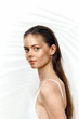 © VICHIZH - Natural beauty portrait of a young woman with long hair in a white dress, against a neutral background with soft shadows.