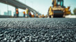 © Yurij - Freshly paved asphalt road surface with construction workers and heavy machinery working under a clear blue sky near an elevated highway structure