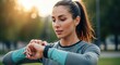 © Nelya - Young Woman Checking Smartwatch During Outdoor Workout in Park.
