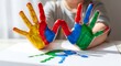 © kagraphixion - Child's hands covered in colorful paint making handprints finger paint