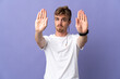 © luismolinero - Young handsome blonde man isolated on purple background making stop gesture and disappointed