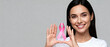© Kamran - Smiling young woman happily holding a pink awareness ribbon perfect for supporting breast cancer survivors and charity
