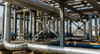 © IMOTIONart - Industrial Plant With Complex Network of Silver Metal Pipes and Blue Valves Under Clear Sky