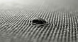 © haris - Extreme close-up macro photograph of a small hole in a woven fabric, showing frayed threads and the intricate texture of the material.