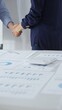 © rogerphoto - Professional businesspeople concluding deal, shaking hands near financial paperwork, calculator, pen on pristine workspace surface. Handshake concept