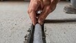 © Justlight - Closeup of a backer rod being inserted into a garage floor expansion joint workers hand in focus surrounding concrete edges softly blurred.