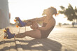© KONSTANTIN SHISHKIN - Young woman lacing up roller skates on pavement