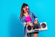 © deagreez - Young woman with boombox in retro 80s style outfit holding cassette player while wearing pink sunglasses and denim jacket, vibrant pop fashion portrait conveying fun and energetic music vibes