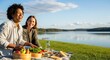 © PrabuanaAndika - Two diverse women laughing during a healthy picnic by a beautiful sunn