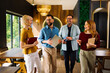 © djile - Happy business colleagues walking and laughing together in modern workspace