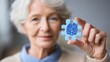 © vetrana - Elderly woman holds jigsaw puzzle piece with brain symbol to represent Alzheimer's disease and memory loss on World Alzheimer's Day