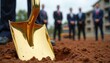 © Pete - Golden shovel in dirt marks new construction. Businessmen in suits attend groundbreaking ceremony. Future building development project starts now. Real estate investment begins.