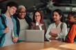 © Zamrznuti tonovi - Diverse group of multi ethnic students and a female teacher gathering around a laptop, working on a project and learning together