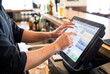 © Stitch - Bartender hands tapping drink order into wet electronic touchscreen POS system at bar counter