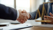 © Lemonkey - Close up handshake between two people across a desk in a law office, symbolizing legal agreement, partnership, trust, and professional business deal