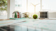 © Phushutter - Miniature eco home models with solar panel and wind turbine on a desk, suggesting sustainable architecture, renewable energy planning, and green building design.