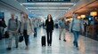 © 5 Grace Media - Businesswoman standing in a busy airport terminal with motion blur people around her.