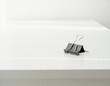 © Tokonya - Minimalist black binder clip on a clean white office desk surface for organization and documentation