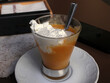 © Ilarialapreziosa - Tipica granita siciliana alla pesca servita in un bicchiere di vetro con abbondante panna montata fresca, dessert estivo artigianale italiano su piattino bianco