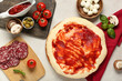 © Pixel-Shot - Pizza dough with tasty tomato sauce and ingredients on light background