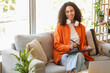 © Pixel-Shot - Female African-American interior designer working with graphic tablet on sofa in office