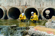 © FotoArtist - Workers conduct tests near water outlet in city during daytime for environmental assessment