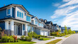 © Nataliya - Row of modern suburban houses with green lawns and garages under a clear blue sky, peaceful residential neighborhood background concept, with copy space