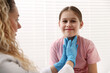© New Africa - Endocrinologist in medical gloves examining girl's thyroid gland in clinic