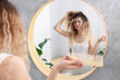 © New Africa - Unhappy woman trying to brush her tangled hair near mirror in bathroom