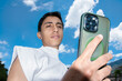 © Laura Herrera/Stocksy - Young Man Holding Smartphone Against Blue Sky With Clouds