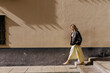 © Tania Cervian/Stocksy - Woman walking urban street with sunlight