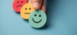 © oksa_studio - Customer satisfaction feedback hand holding happy neutral and sad icons on blue background client experience mood