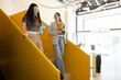 © VICTOR TORRES/Stocksy - Colleagues walking down bright yellow office staircase