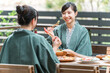 © buritora - Young Asian women on a girls' trip to a ryokan (Japanese inn) or hot spring inn where they dine on a balcony or wooden deck.
