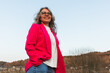 © Diego Martin/Stocksy - Confident woman in pink blazer standing outdoors against clear sky
