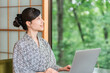 © buritora - A woman in a yukata working on her laptop in a room at a hot spring inn.