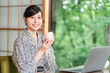 © buritora - A young Asian woman in a yukata (traditional Japanese robe) drinking tea in a Japanese-style room at a ryokan (traditional Japanese inn).