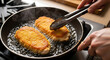 © Its_RDP - Delicious breaded chicken cutlets sizzling in hot oil in a frying pan, being flipped with tongs for a perfect golden-brown crust