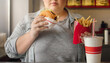 © Happy - Person eats a burger fries and soda at a fast food restaurant. for food blogs, social media ads, and unhealthy eating concept.