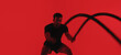© peopleimages.com - Man, fitness and battle rope in studio with exercise, strength training and intense physical activity. Mockup space, person and workout with endurance challenge, cardio or wellness on red background