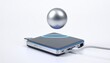 © desistudio - A metallic sphere levitates above a magnetic charging pad, showcasing wireless power technology.
