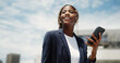 © peopleimages.com - Thinking, business and black woman in city, cellphone for social media or ideas for news report. Low angle, person or journalist in street, smartphone or reflection for article or deadline for column